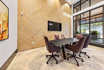 A conference room with a table and chairs and a tv on the wall.
